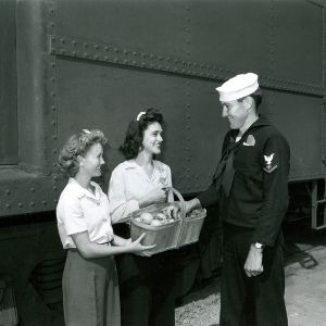 Two women offer food to a seaman